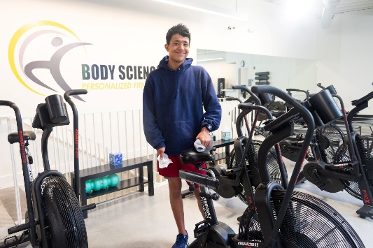 A person standing next to exercise bikesDescription automatically generated